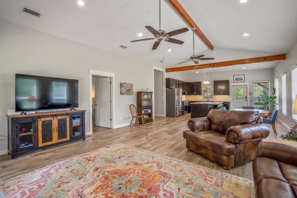 Spacious open-concept living area with high ceilings and exposed wooden beams.