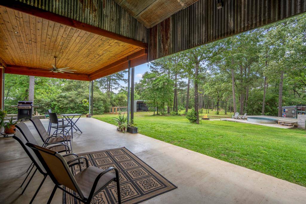 The home showcases a spacious covered patio with a wooden tongue and groove ceiling and ceiling fan. Perfect for outdoor relaxation.