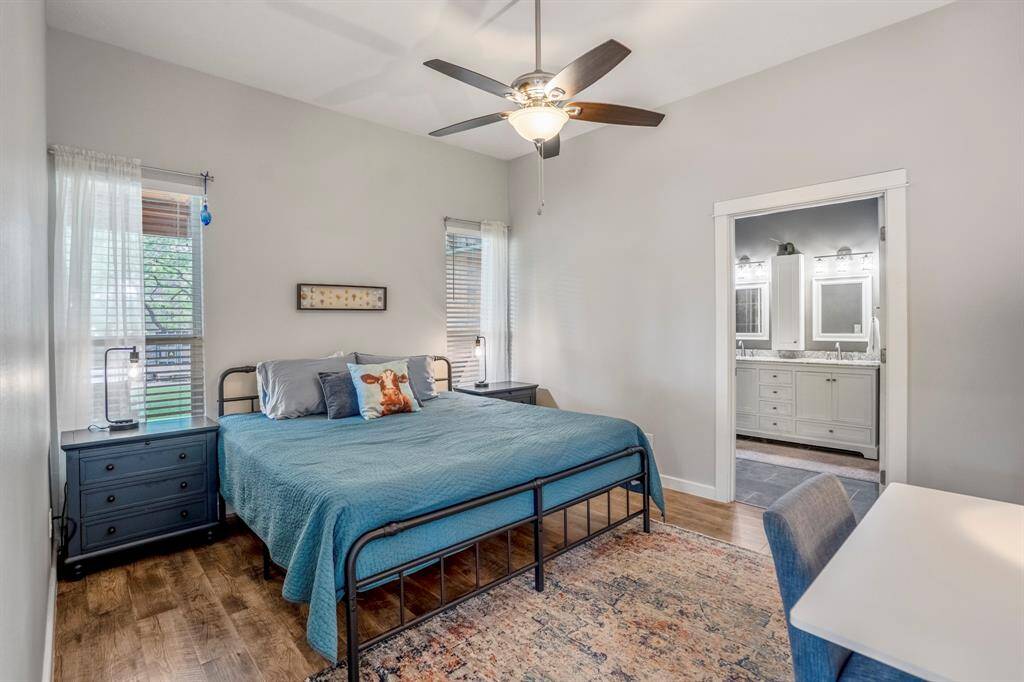 The cozy primary bedroom features a ceiling fan, natural light from two windows, and a spacious layout. It includes an en-suite bathroom with dual sinks and elegant finishes, perfect for comfort and convenience.
