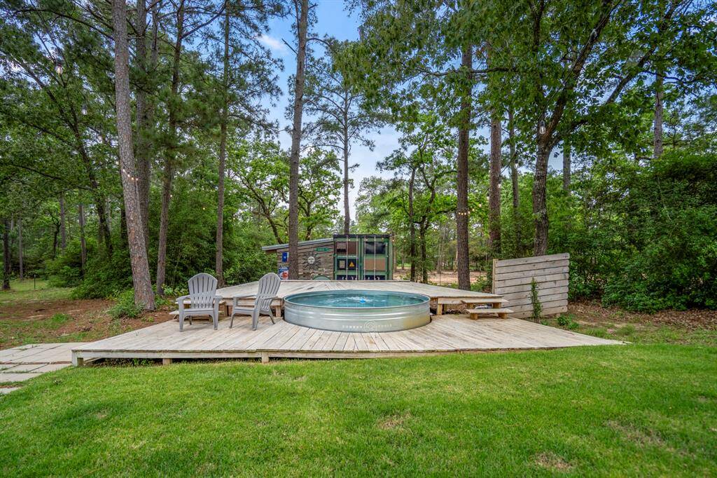 The custom built wooden deck boast a stock tank pool, surrounded by lush greenery and tall trees, offering a peaceful retreat.