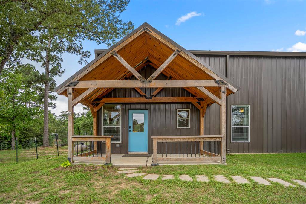 Charming modern home with a rustic touch featuring a covered wooden porch, a bright blue front door is such a fun way to welcome your guests!