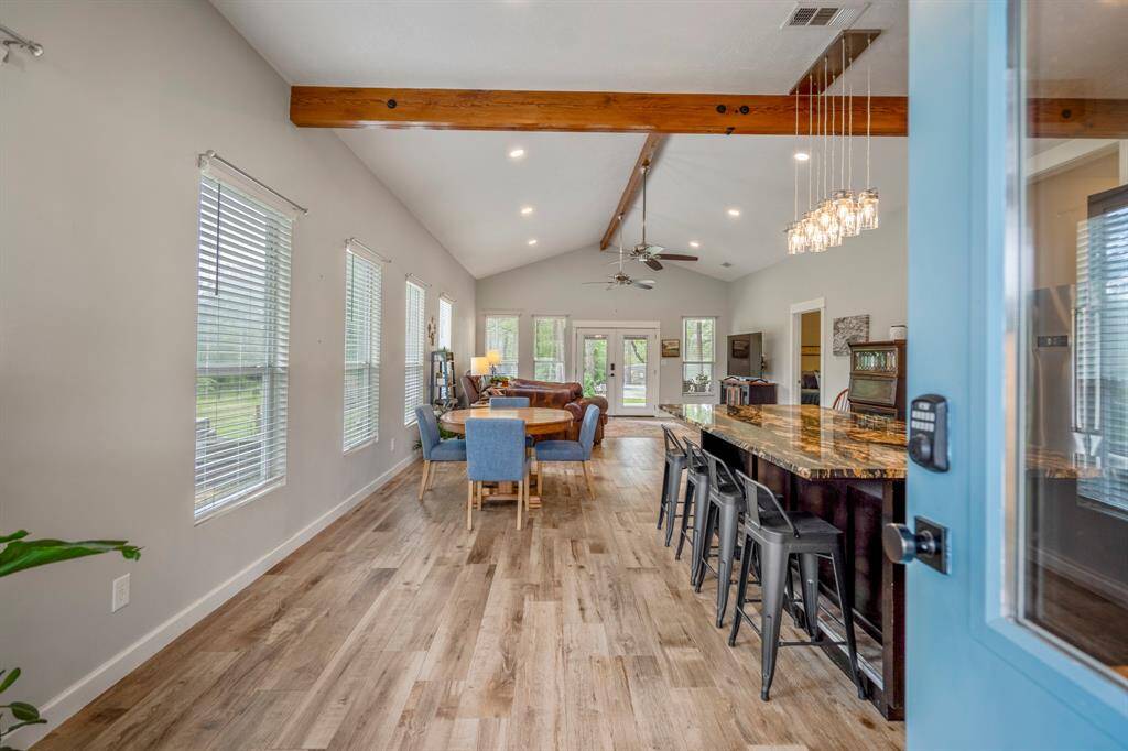 The home features open-concept living space with high ceilings and exposed wooden beams.  Abundant natural light from multiple windows, and a blend of modern and rustic elements.