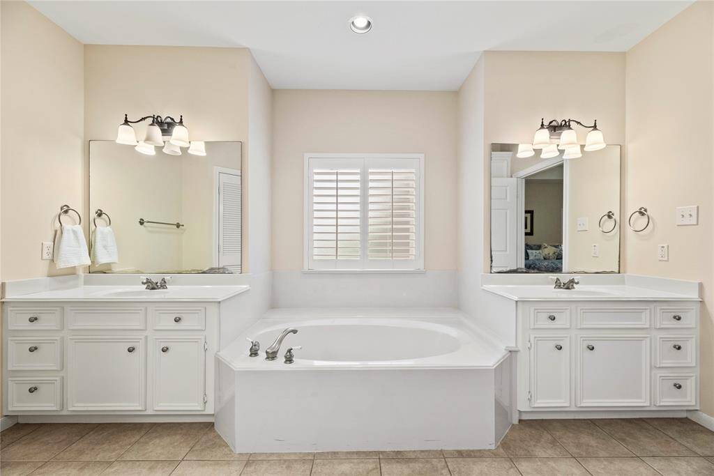 The primary bath features dual vanities, providing ample personal space along with an abundance of custom cabinetry for seamless organization.