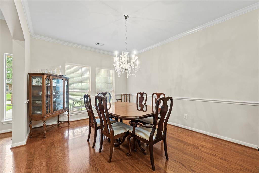 Just to the left of the entryway, the formal dining room awaits—elegantly appointed with chair rail detailing, a classic chandelier, and sophisticated crown molding.