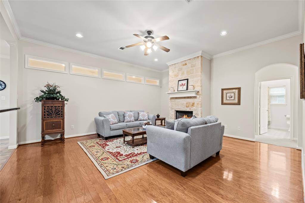 Step into the spacious living area, featuring rich wood floors and a striking limestone fireplace that serves as a warm, elegant focal point.