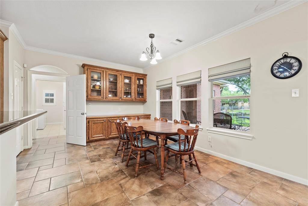 The charming breakfast room features additional cabinetry perfect for showcasing stemware, a graceful chandelier, and easy-care tile flooring for everyday elegance.