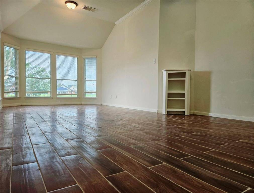 A spacious primary suite with high ceilings and a curved wall of windows offering sweeping views of the backyard and lake—an ideal setting for restful mornings and peaceful nights.