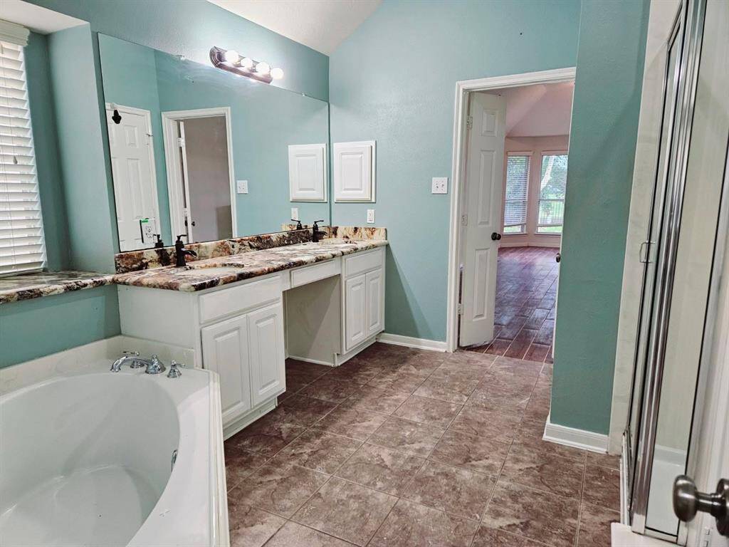 Retreat to a rejuvenating bath featuring a deep soaking tub, dual-sink vanity with under-storage, and a wide mirror that enhances the sense of space and light.