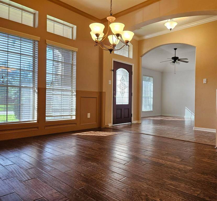 Step into a bright and welcoming entry framed by transom windows and abundant natural light. A private study sits to the left, while an inviting den opens to the right, setting the tone for the home’s spacious interior.