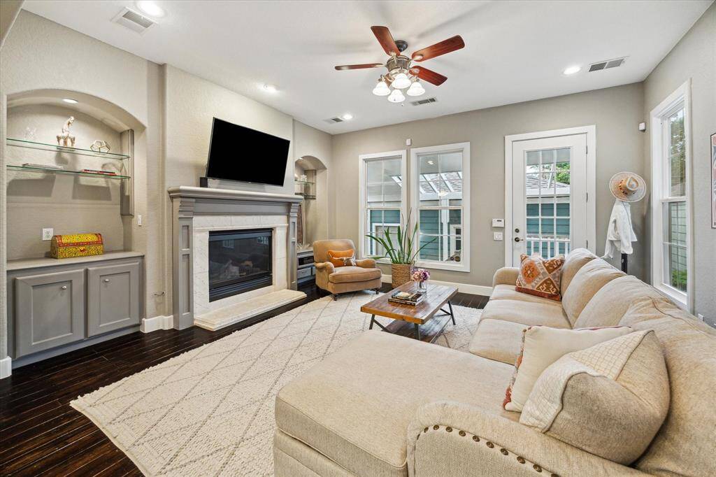 The living room features a gas log fireplace, flanked on either side by built-ins and storage. From the living room there is access to the courtyard and two car garage.