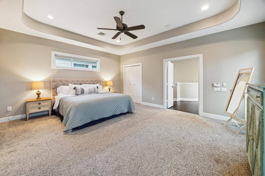 Expansive primary suite with dual closets, tray ceiling, recessed lighting and ceiling fan.