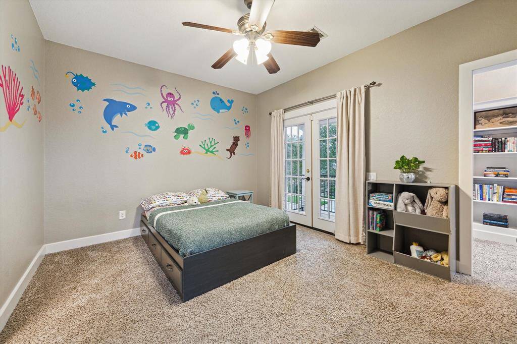 Secondary bedroom with a walk-in closet, ceiling fan, access to the bathroom, French doors leading to a covered balcony overlooking the front yard and even has a cozy reading nook!