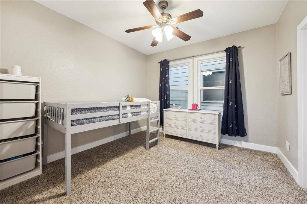 Secondary bedroom with ceiling fan, two large windows, closet and access to the bathroom.