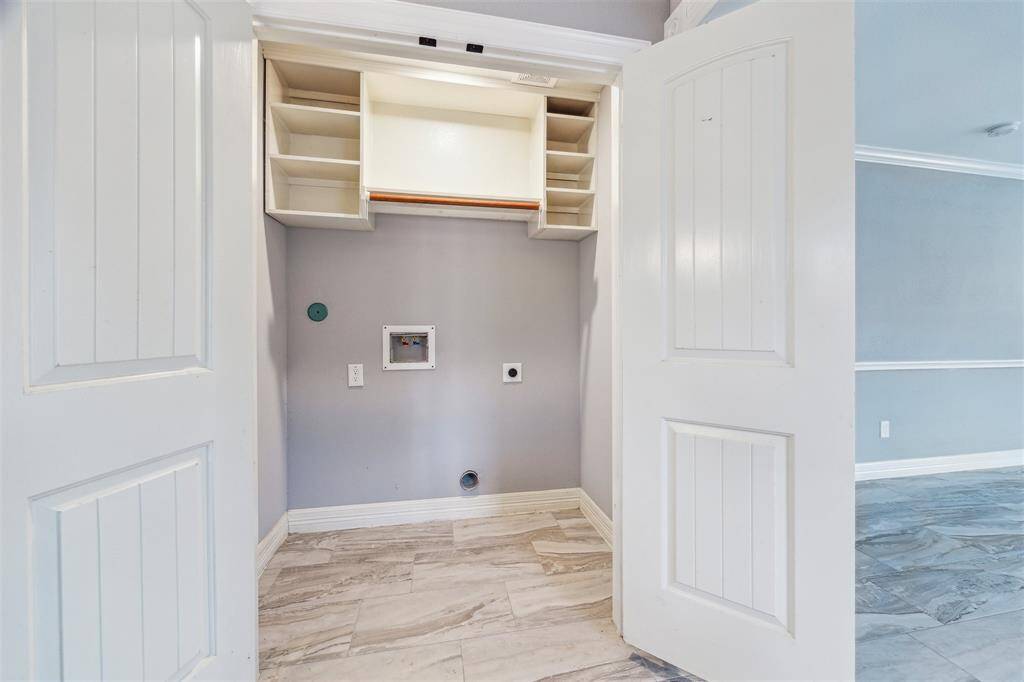 Laundry closet just off of the kitchen, with upper storage shelves. Washer and electric dryer hookups.