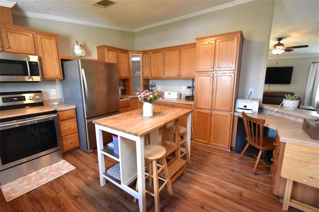 Charming kitchen with warm wood cabinets, stainless steel appliances, and a central island with seating. Features ample storage, a cozy workspace, and an open layout connecting to the living area.