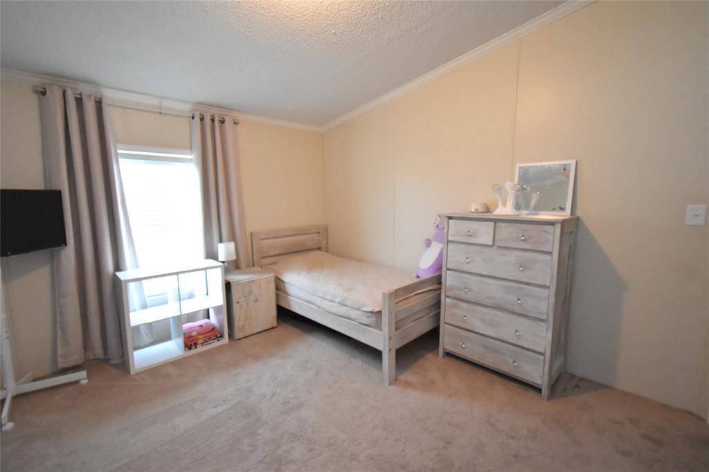 Cozy bedroom with neutral color walls. The space is carpeted and well-lit, perfect for a child's room or guest space.
