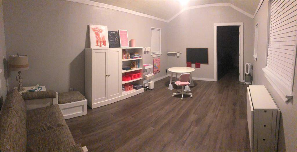 This room inside the small school house, features a cozy, well-lit space with a soft gray color scheme, ideal for a playroom or study. It includes toilet and sink.