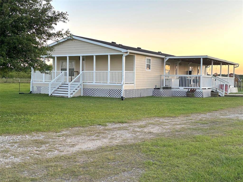 Charming single-story home with a welcoming front porch and covered side deck. Set on a spacious, grassy lot with a gravel driveway, perfect for enjoying peaceful outdoor living.