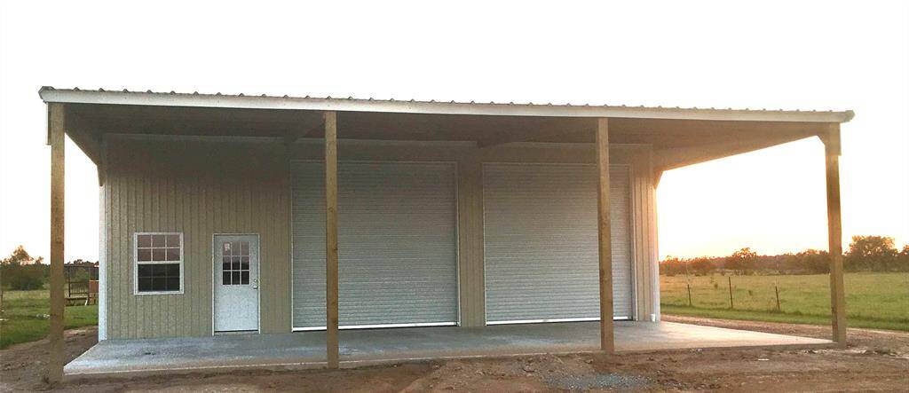 This photo shows a metal shop building with a large covered awning. It features 3 large roll-up garage doors and entry door.