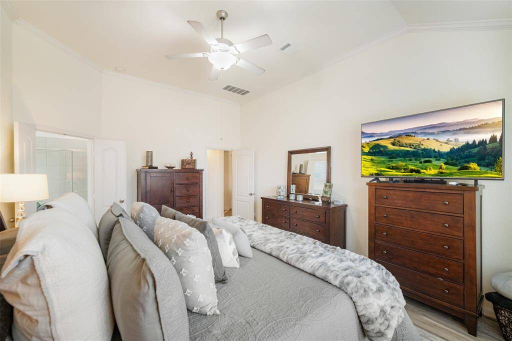 The primary suite with wood tile floors, ceiling fan and double door access to the on suite primary bathroom!