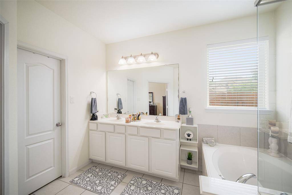 Spacious primary bathroom featuring double sinks, a separate soaking tub and walk in shower and stylish tile flooring for a clean, modern look!
