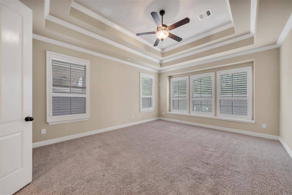 This spacious primary bedroom is filled with natural light, thanks to its large windows that create a warm, airy atmosphere.