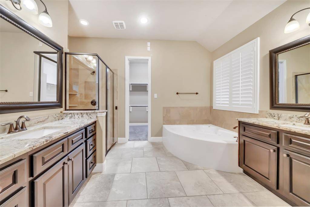 This beautifully designed primary bathroom offers a spacious layout, providing both comfort and style. Enjoy a modern glass-enclosed shower and a relaxing soaking tub, perfect for unwinding after a long day.