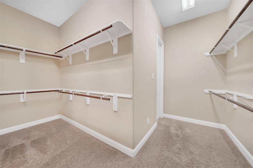 This generously sized primary closet offers an abundance of storage space, designed to accommodate all your wardrobe needs with ease.