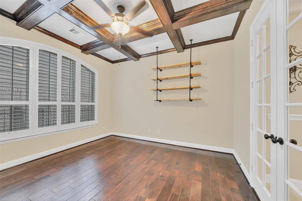 This stylish study features rich wood floors, classic plantation shutters, and a stunning coffered ceiling, adding character and charm. Double glass doors provide an elegant entry, making it a perfect space for work or relaxation