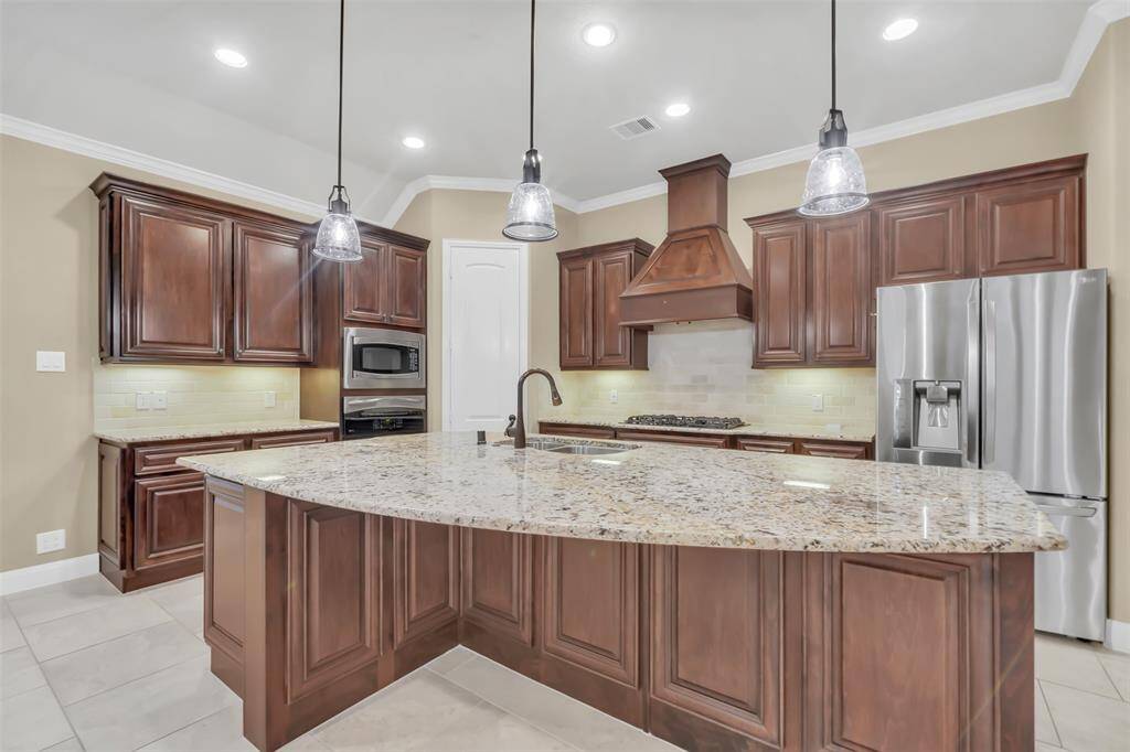 This beautifully designed kitchen features elegant wood cabinetry, durable granite countertops, and high-end stainless steel appliances.