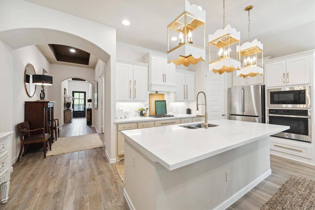 View of the kitchen and entry hall.  This two-tone kitchen is both beautiful and functional.  It features quartz counters, a big island, 5-burner gas stove, and tons of storage including a walk-in pantry.  Stainless steel appliances include a top of the line Maytag dishwasher and a Bosch refrigerator (included).