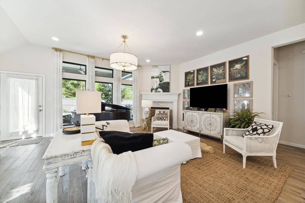 The transoms above the windows allow more natural light in and the floor-to-ceiling curtains help bring attention to the high ceiling. Enjoy cozying up to the corner fireplace on chilly nights. The center light was chosen to coordinate with the kitchen pendants.