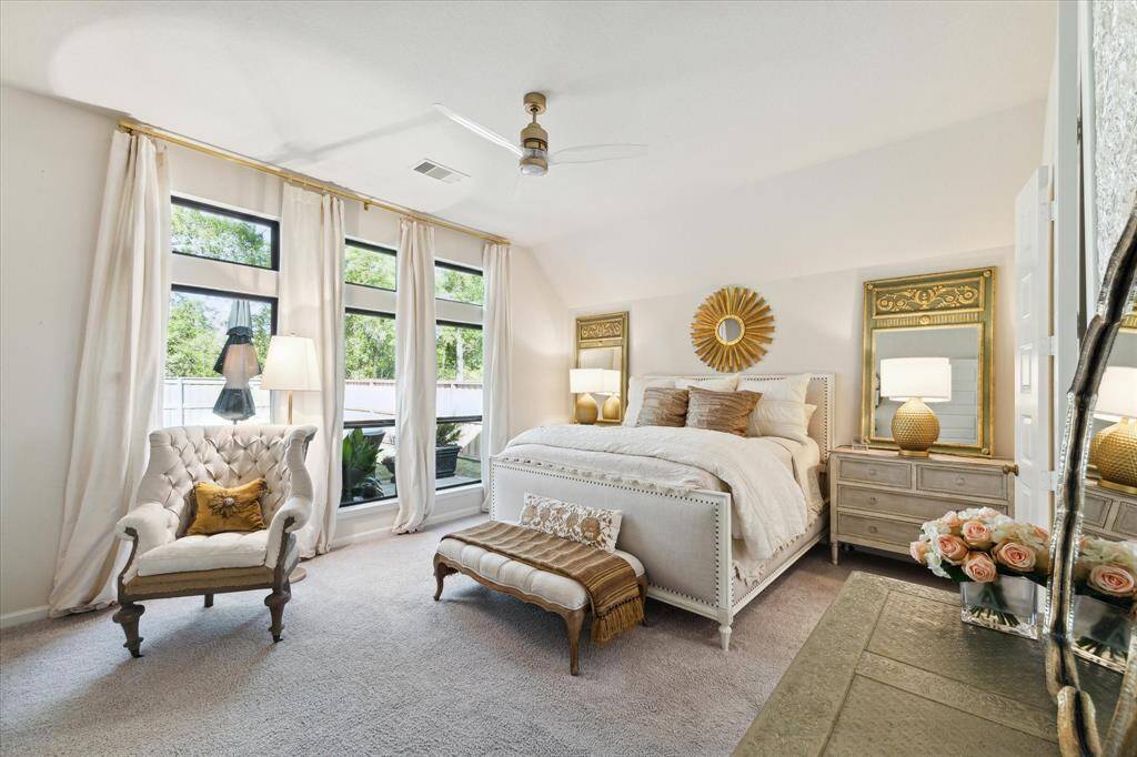 Welcome back inside to your primary ensuite.  This spacious bedroom is a true retreat that overlooks the backyard, has a high ceiling, and room for a sitting area.  Enjoy a restful sleep with the cream-toned Thai silk curtains that have a blackout lining from Restoration Hardware and an on-trend ceiling fan to help keep you cool!