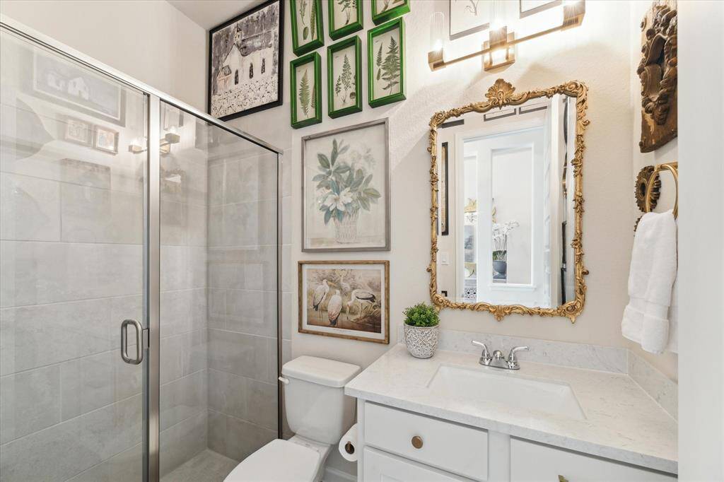The guest bathroom features a large welk-in shower and upgraded lighting and a designer mirror.
