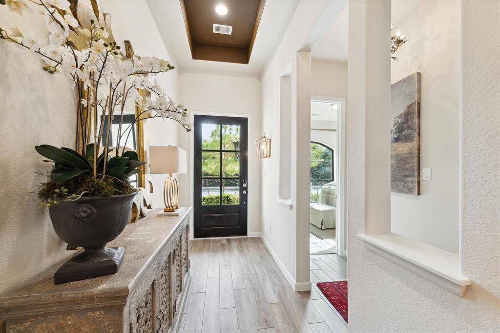 This airy entryway is the perfect spot to greet your guests with a 13 foot tray ceiling and a beautiful wall sconce from Neiman Marcus. Looking out of the front door you will see a blanket of trees across the street. No front neighbors!