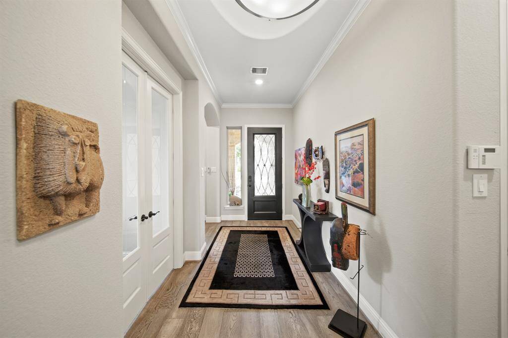 Wood flooring at the entryway of the home. At the front of the home is a bedroom, full bathroom, and the study.