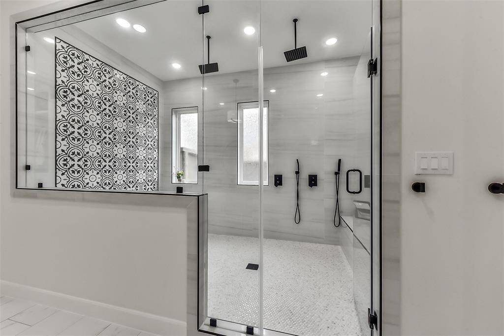 Experience luxury in this stunning, spacious shower featuring elegant patterned tiles and modern fixtures. The sleek design and ample natural light create a perfect oasis for relaxation.