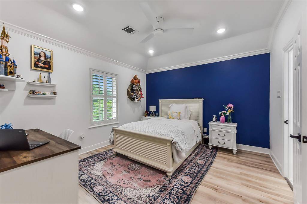 Spacious bedroom featuring a vibrant accent wall, elegant hardwood floors, and ample natural light. Perfect for relaxation and comfort.