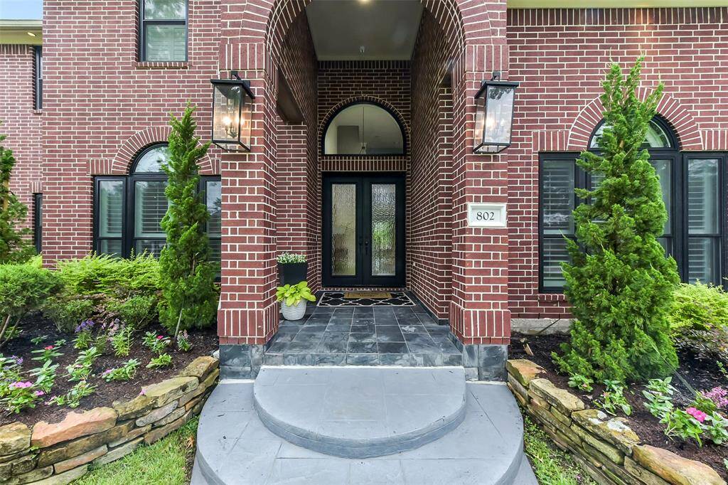 Welcome to your elegant new home! This stunning brick exterior features a grand arched entryway, complemented by lush landscaping and modern lighting. Step inside to discover timeless charm and sophistication.