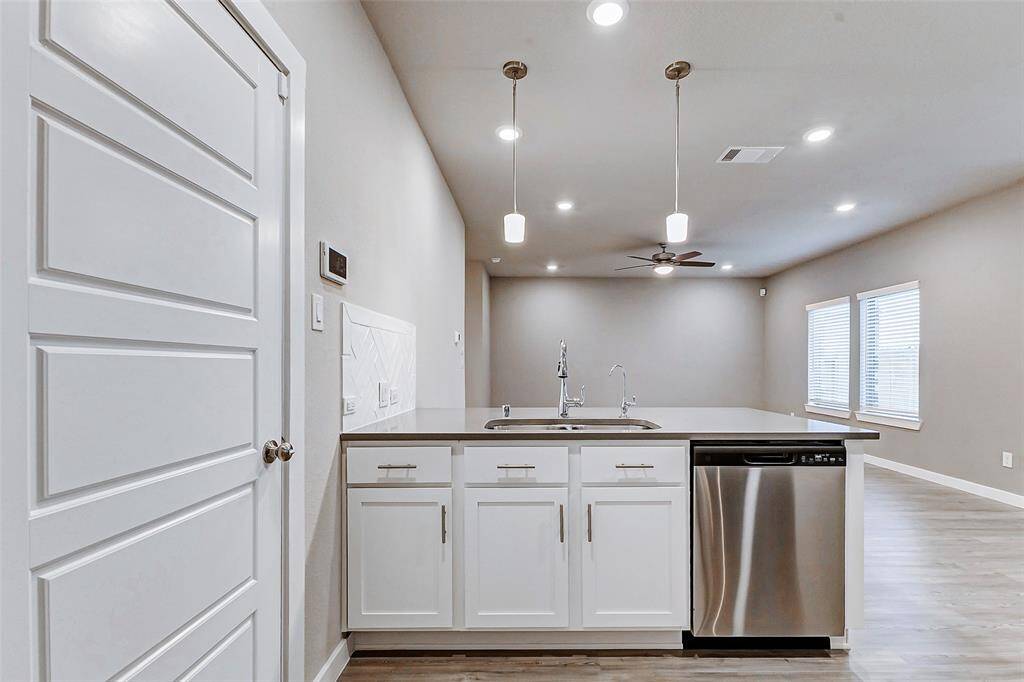 The chef’s kitchen opens seamlessly to the living area, making entertaining a breeze. Enjoy stainless steel appliances, quartz counters, and custom tilework, all illuminated by stylish pendant lights.
