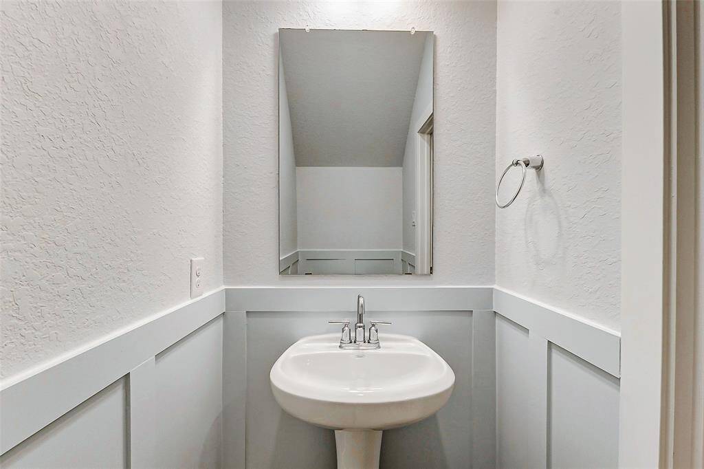 The half bath on the main floor exudes charm with custom wainscotting and upgraded paint finishes. Modern lighting and a pedestal sink make this a convenient and stylish space for guests. A perfect balance of function and design!