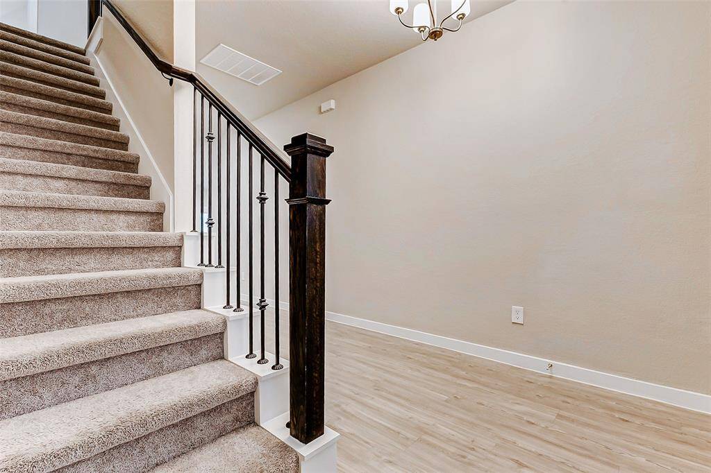 Step into an inviting foyer with wood-like laminate flooring and modern recessed lighting. The staircase features elegant iron spindles, adding sophistication to the bright and open layout. This well-designed entryway is a welcoming introduction to the home’s seamless blend of style and function.