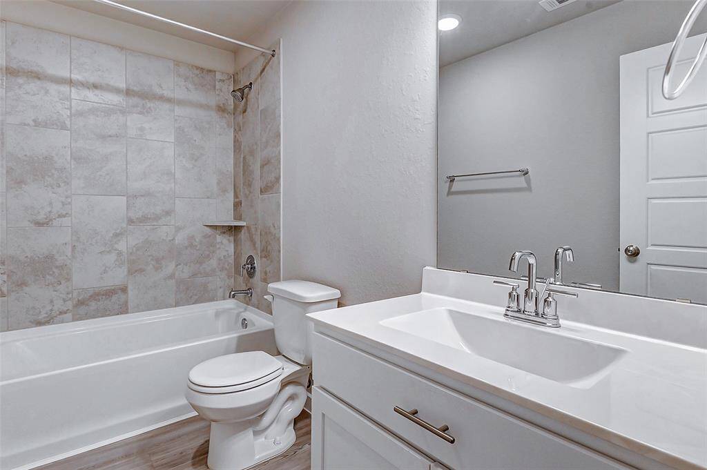 The guest bathroom offers a stylish design with a combination tub and shower, modern fixtures, and neutral tones. A functional and elegant space for family and visitors alike.
