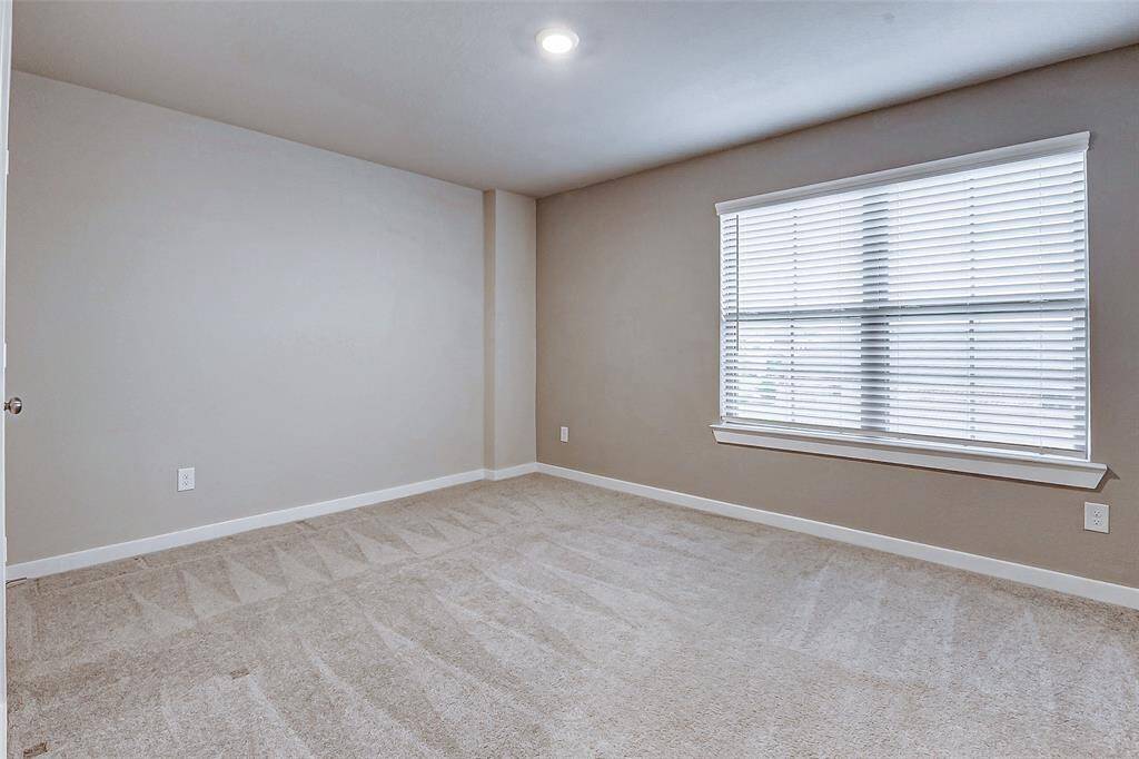 This secondary bedroom boasts soft carpeting, a large window for natural light, and ample space for rest or play. A peaceful retreat for guests or family.