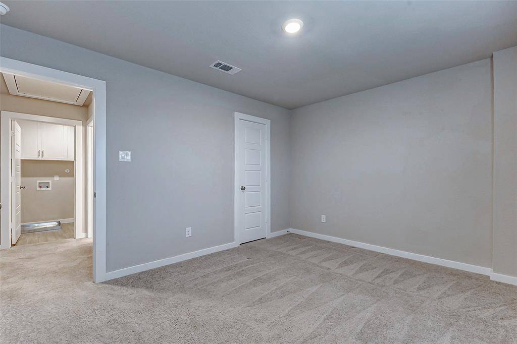This versatile bedroom offers plush carpeting and neutral tones, making it an ideal space for guests, a home office, or a cozy retreat. The nearby laundry access adds convenience without compromising privacy.