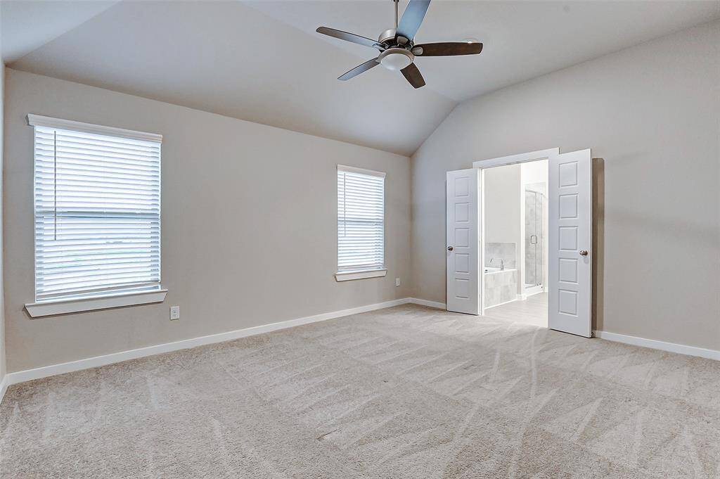 The airy primary bedroom features soaring ceilings and ample natural light, creating a tranquil retreat. Dual windows and a contemporary ceiling fan enhance the serene atmosphere. Conveniently connected to an en suite bath, this bedroom is the perfect personal sanctuary.