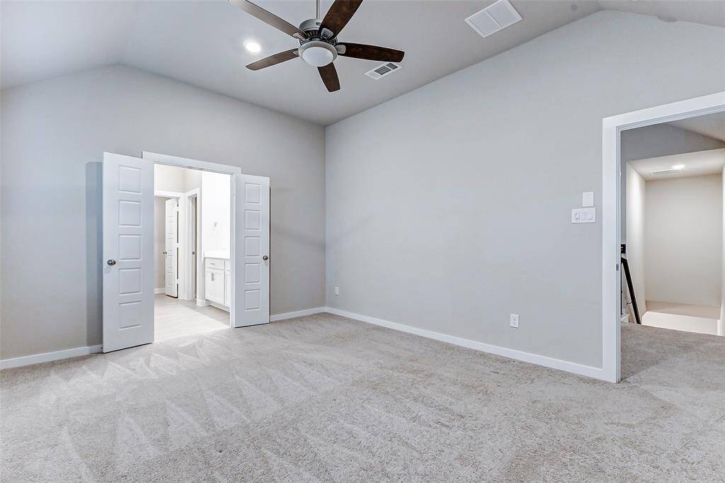 A second angle of the primary suite showcases its generous layout, complete with cozy carpeting and easy access to the spa-inspired en suite bath. The neutral palette and thoughtful design make this room a haven of relaxation and comfort.