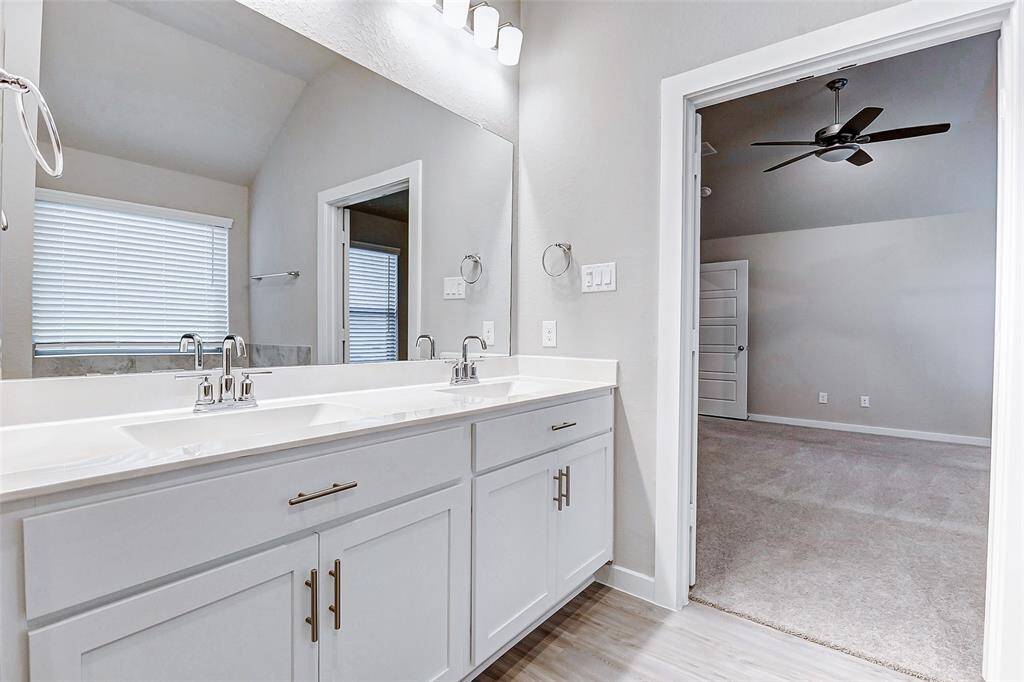 A sleek double vanity with polished fixtures enhances the spa-like appeal of the primary bathroom. With plenty of storage and a modern design, this bathroom offers both style and functionality.