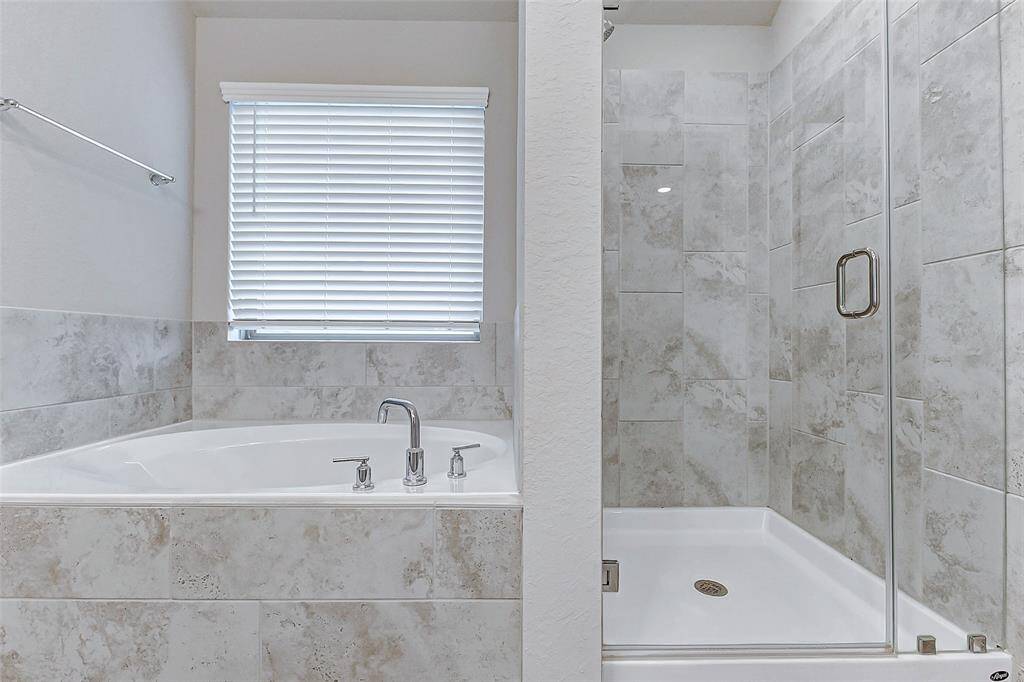 Enjoy the best of both worlds in this en suite bath, featuring a walk-in shower and soaking tub. Natural light pours in through the window, illuminating the serene, spa-inspired finishes.