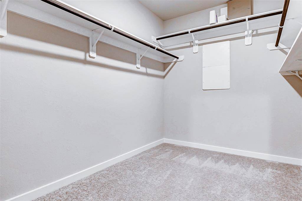 An expansive walk-in closet that provides ample storage with multiple shelves and hanging rods. The neutral tones and plush carpeting ensure this functional space is as inviting as the rest of the home.